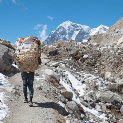 Nepalian Porter carrying heavy load on his back to Everest Base camp. Himalayas. Nepal.